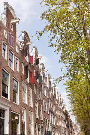 Facades of canal houses on leidsegracht in centre of amsterdam with green trees in springの写真素材