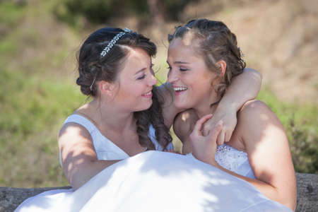 two brides smile and embrace in nature surroundings on sunny dayの写真素材