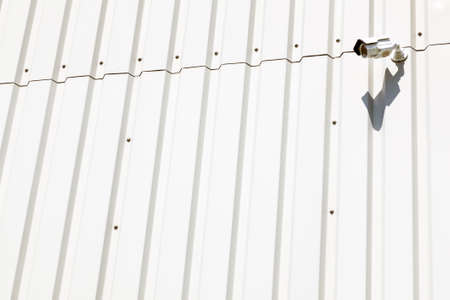 surveillance camera on wall of white industrial metal building