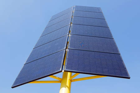 solar panels in two directions on yellow metal stand and blue sky