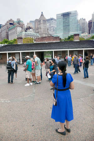 tourists take photographs within the walls of castle clinton in battery park with manhattan skyline in the backgroundのeditorial素材