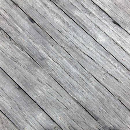 old rough wheathered battered textured grey wooden planks with cracks diagonally placedの写真素材