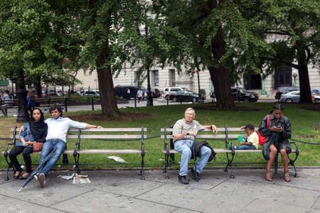 people of several races sit on bench in downtown manhattan new york city near city hall and brooklyn bridgeのeditorial素材