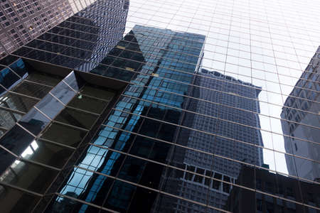 glass facade of skyscraper in new york downtown manhattan with reflections of other skyscrapers and skyの写真素材
