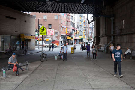 people sit and walk under beginning of manhattan bridge in chinatown manhattan new york cityのeditorial素材