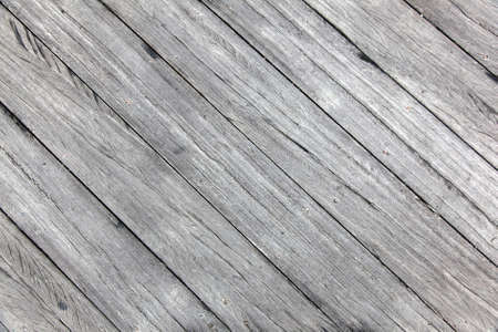 old rough wheathered battered textured grey wooden planks with cracks diagonally placedの写真素材