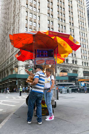 vendor sells hot dogs and pretzels on the street in new york city and talks to a womanのeditorial素材