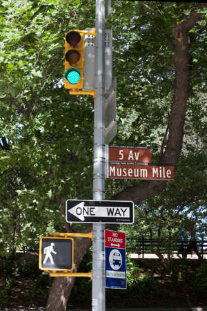 traffic light and sigh indicating museum mile on 5 av new york city against green foliage of central parkの写真素材