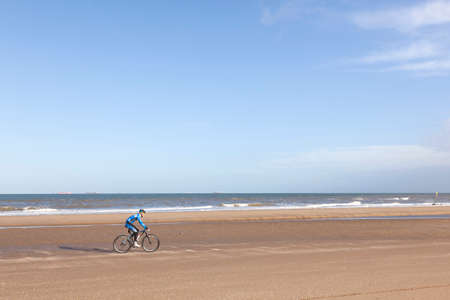 scheveningen, 27 march 2016: man on mountain bike on dutch scheveningen beach with blue skyのeditorial素材