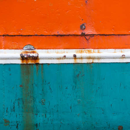 rusty metal bow of old fisher boat hull in orange blue and whiteの写真素材