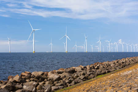 wind turbines in water of ijsselmeer off the coast of flevoland with blue sky in the netherlandsの写真素材