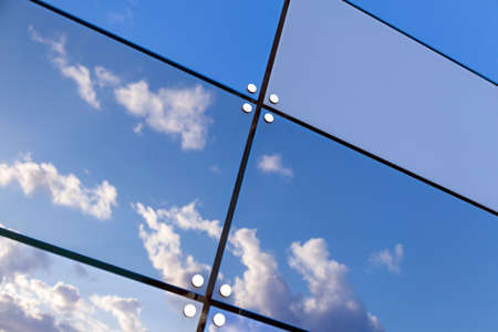 blue sky and white clouds reflect in glass panes of modern buildingの写真素材