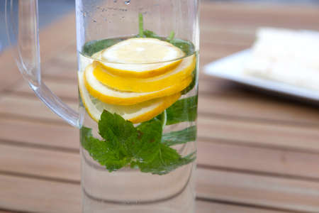 can with water and lemon slices with mint leaves on wooden tableの写真素材