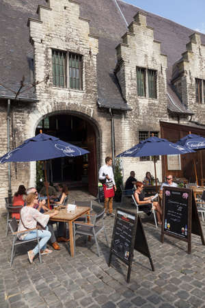 waiter waits on tourists at outdoor cafe in centre of the medieval town Ghent in Belgiumのeditorial素材