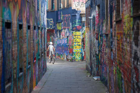 young child on bike between walls full of grafiti in belgian town Ghentのeditorial素材