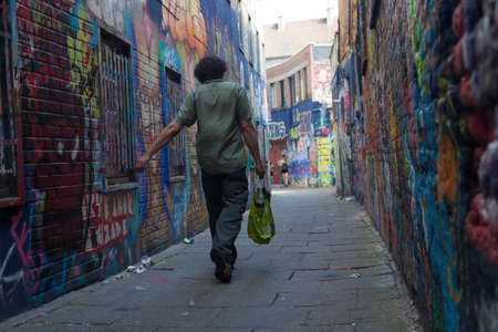 man walks with groceries between walls full of grafiti in belgian town Ghentのeditorial素材