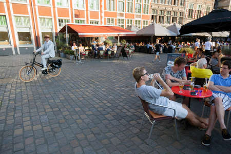 man on bike passes outdoor cafe in medieval centre in belgian town of gentのeditorial素材