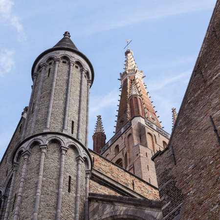 towers of onze lieve vrouw in the old city of brugge in belgium with blue skyの写真素材