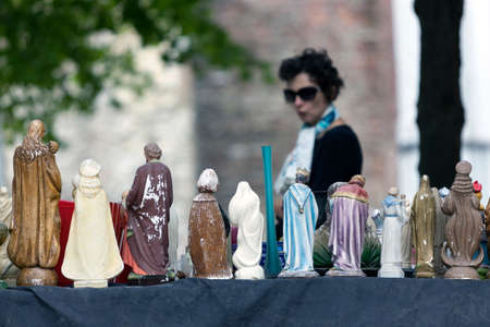 woman looks at virgin mary statues on open air market in the belgian town of brugge