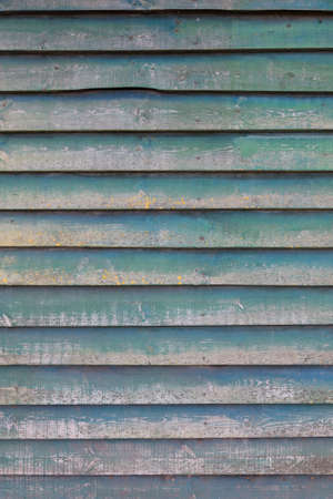 vertical part of shed wall consisting of old horizontal wooden planks with faded green paint and yellow mossの写真素材