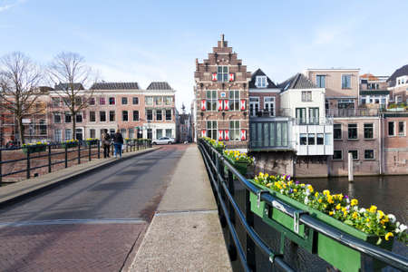 flowers on bridge over river linge and old houses in centre of old dutch town gorinchemの写真素材
