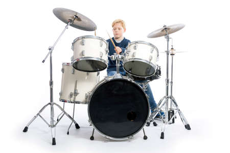 young blond boy drums behind drum kit against white background in studioの写真素材