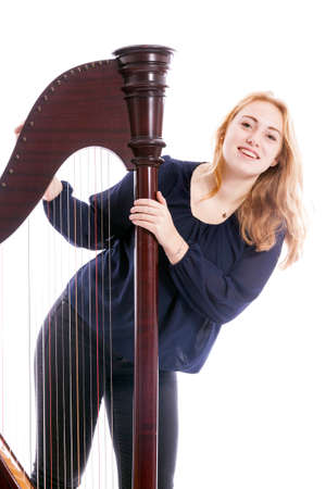 red blond caucasian teenage girl with harp stands on floor against white studio backgroundの写真素材