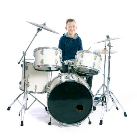 teenage boy behind drum kit in studio against white backgroundの写真素材