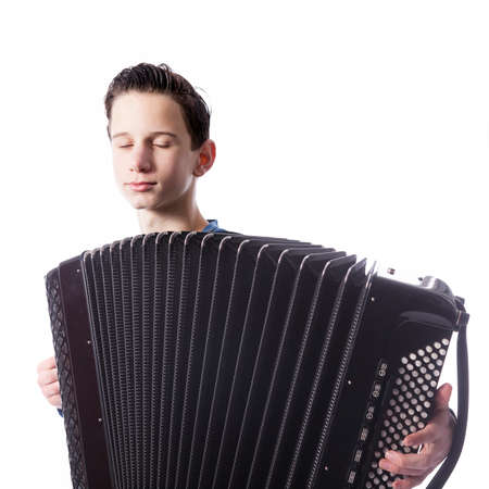 teenage caucasian boy with closed eyes plays the accordion in studio with white backgroundの写真素材
