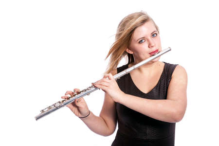 young caucasian blond woman plays the flute against white background in studioの写真素材
