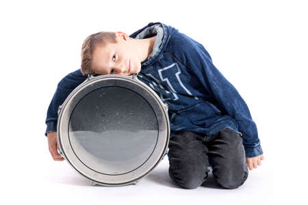 teenage boy sits with drum in studio against white backgroundの写真素材