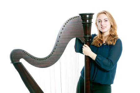red blond caucasian teenage girl with harp stands on floor against white studio backgroundの写真素材