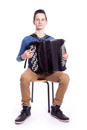 teenage caucasian boy plays the accordion in studio with white backgroundの写真素材