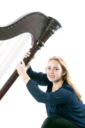red blond caucasian teenage girl with harp sits against white studio backgroundの写真素材