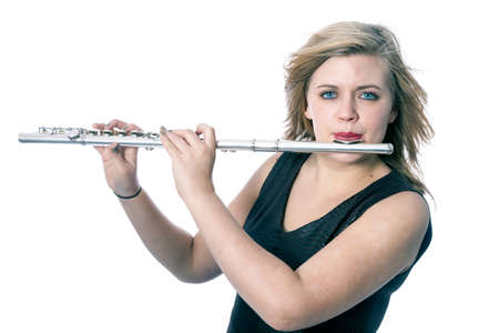 young blond caucasian woman plays the flute against white background in studioの写真素材