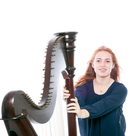 red blond caucasian teenage girl pushes harp  against white studio backgroundの写真素材