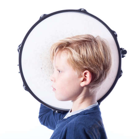 portrait of young blond boy with drum against white background in studioの写真素材