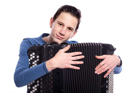 teenage caucasian boy embraces accordion in studio with white backgroundの写真素材