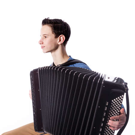 teenage caucasian boy plays the accordion in studio with white backgroundの写真素材