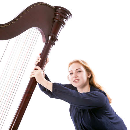 red blond caucasian teenage girl with harp sits against white studio backgroundの写真素材