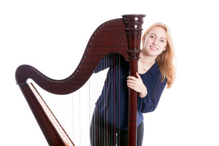 red blond caucasian teenage girl with harp stands on floor against white studio backgroundの写真素材