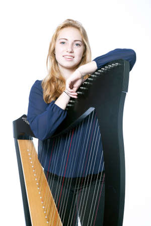 red blond caucasian teenage girl leans on harp against white studio backgroundの写真素材