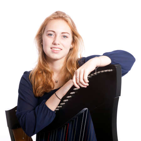 red blond caucasian teenage girl leans on harp against white studio backgroundの写真素材