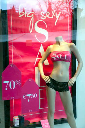 fashion doll wears underwear and sale signs in display window of clothing storeの写真素材