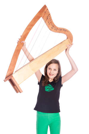young girl in black shirt lifts harp in studio against white background and smilesの写真素材