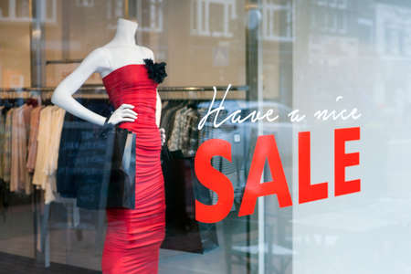 fashion doll with dress for women and the word sale on display window of clothing storeの写真素材