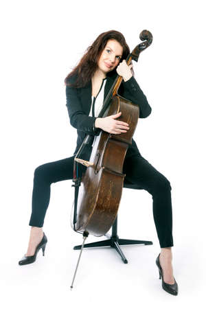 beautiful brunette woman sits with old brown violoncello in studio against white backgroundの写真素材