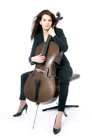 beautiful brunette woman sits with old brown violoncello in studio against white backgroundの写真素材