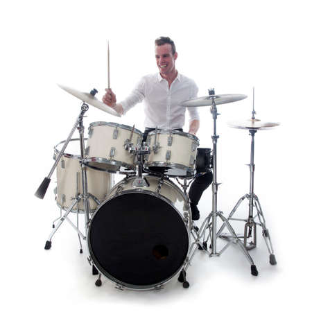 white drummer behind drum set wears white shirt and plays the drums in studio smilingの写真素材