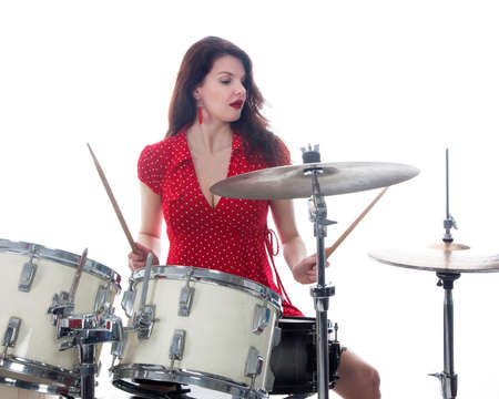 sexy brunette in red dress plays drum kit in studio against white backgroundの写真素材
